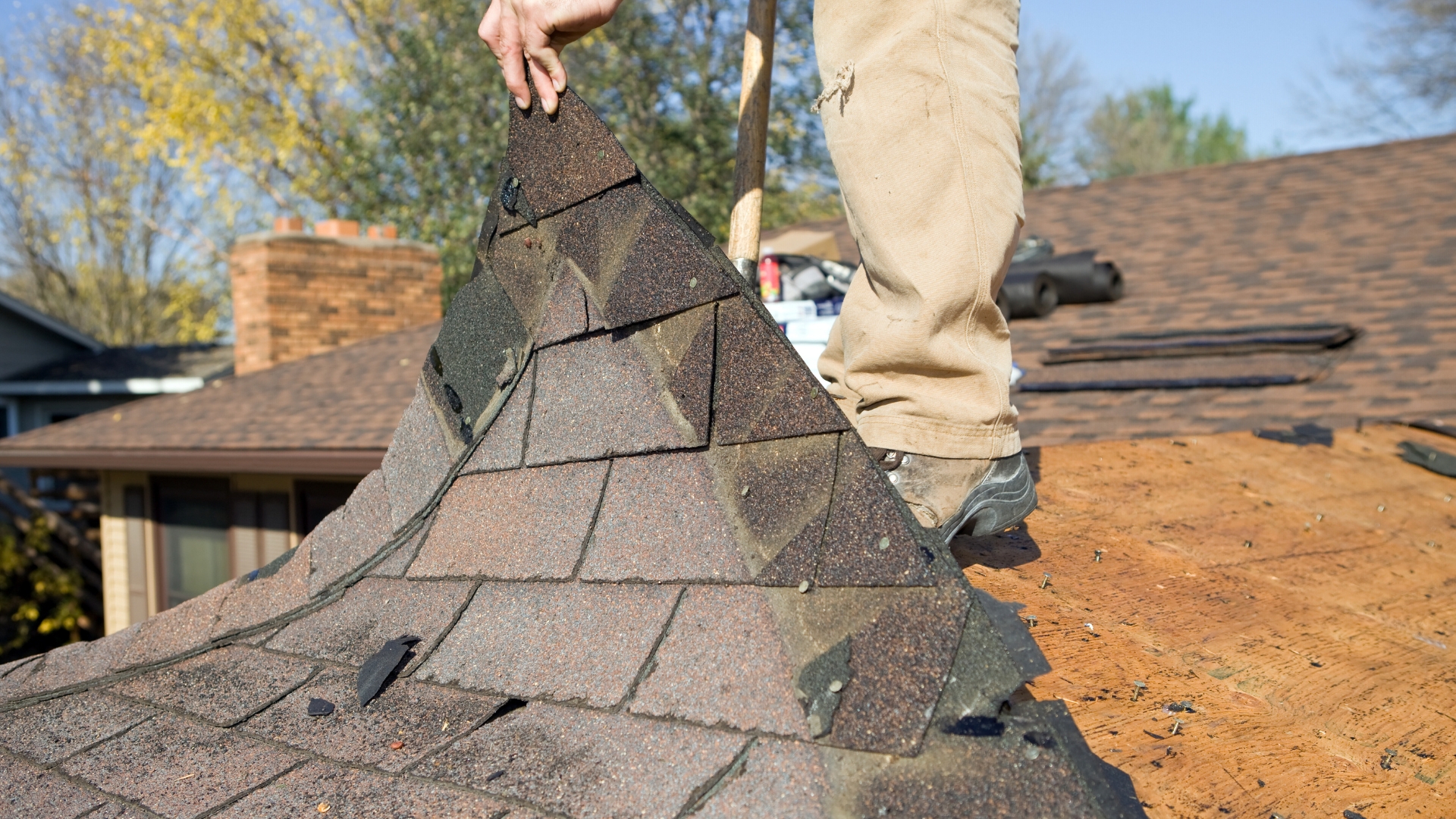 Roof repair underway as shingles are stripped from an aging residential roof