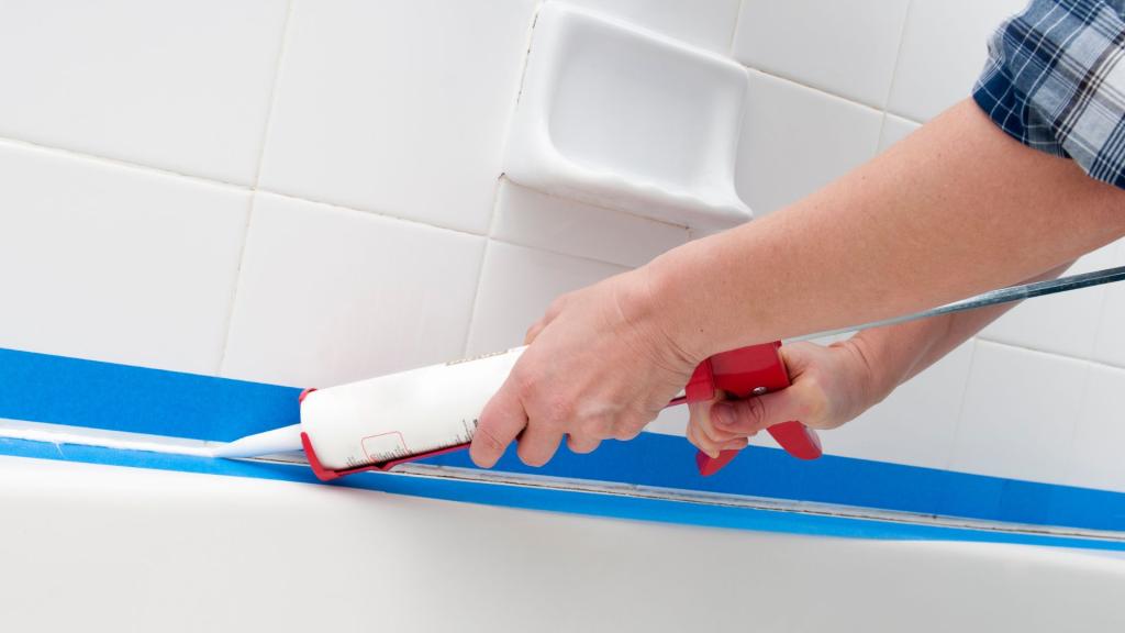 Applying caulk along the bathtub edge as part of waterproofing bathroom maintenance
